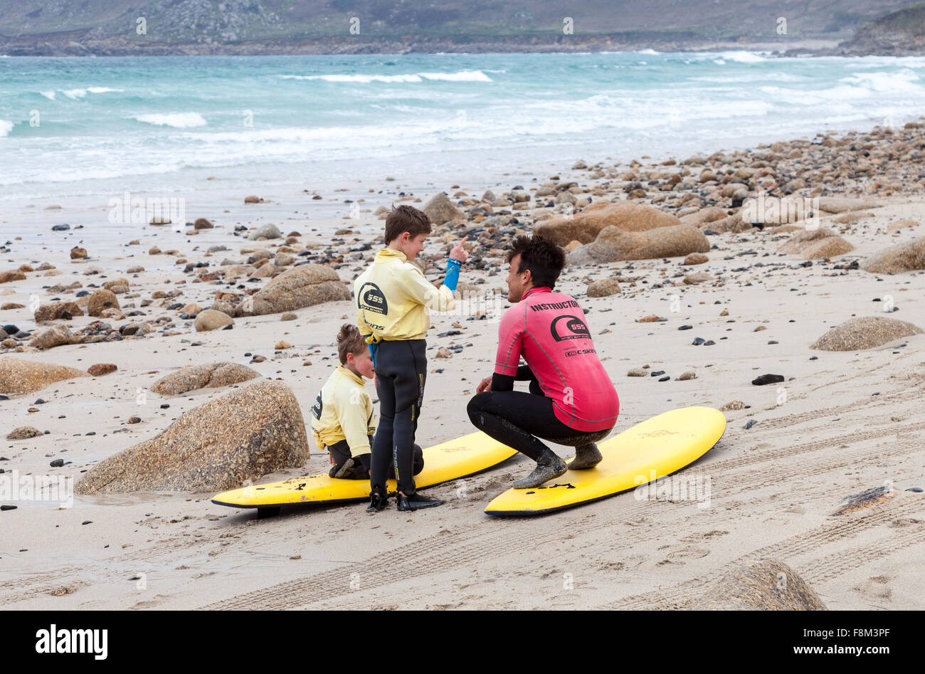 Ein Lehrer und zwei junge männliche Surfer lernen, wie man Surfen auf Surfbretter auf Sennen Cove Strand Cornwall England UK Stockfoto