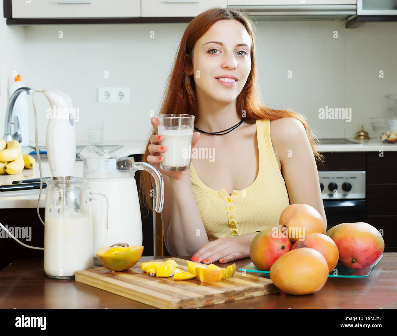 stets gut gelaunte Frau trinken Milch-Shake mit mango Stockfoto