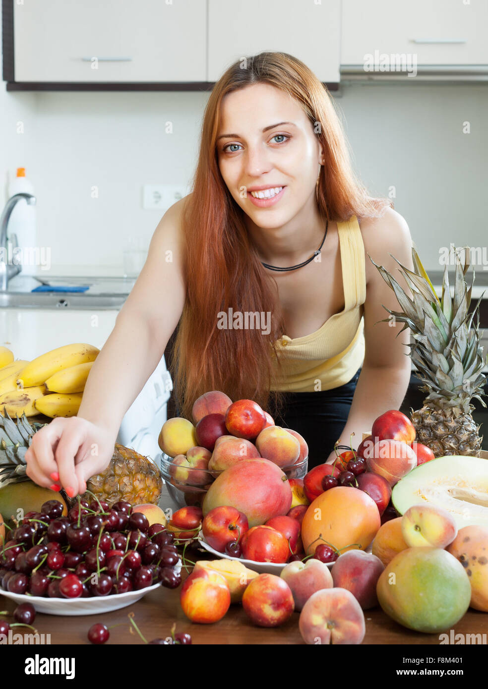 Glückliche junge Hausfrau mit reifen Früchten am heimischen Küche Stockfoto