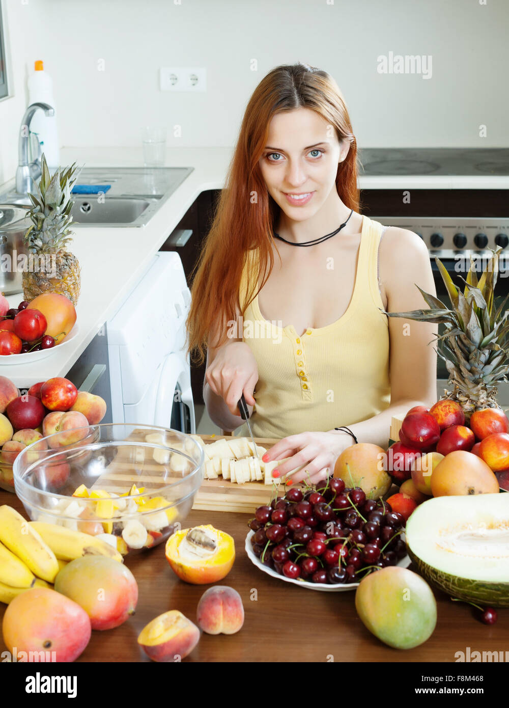 Glückliche junge Hausfrau mit reifen Früchten am heimischen Küche kochen Stockfoto