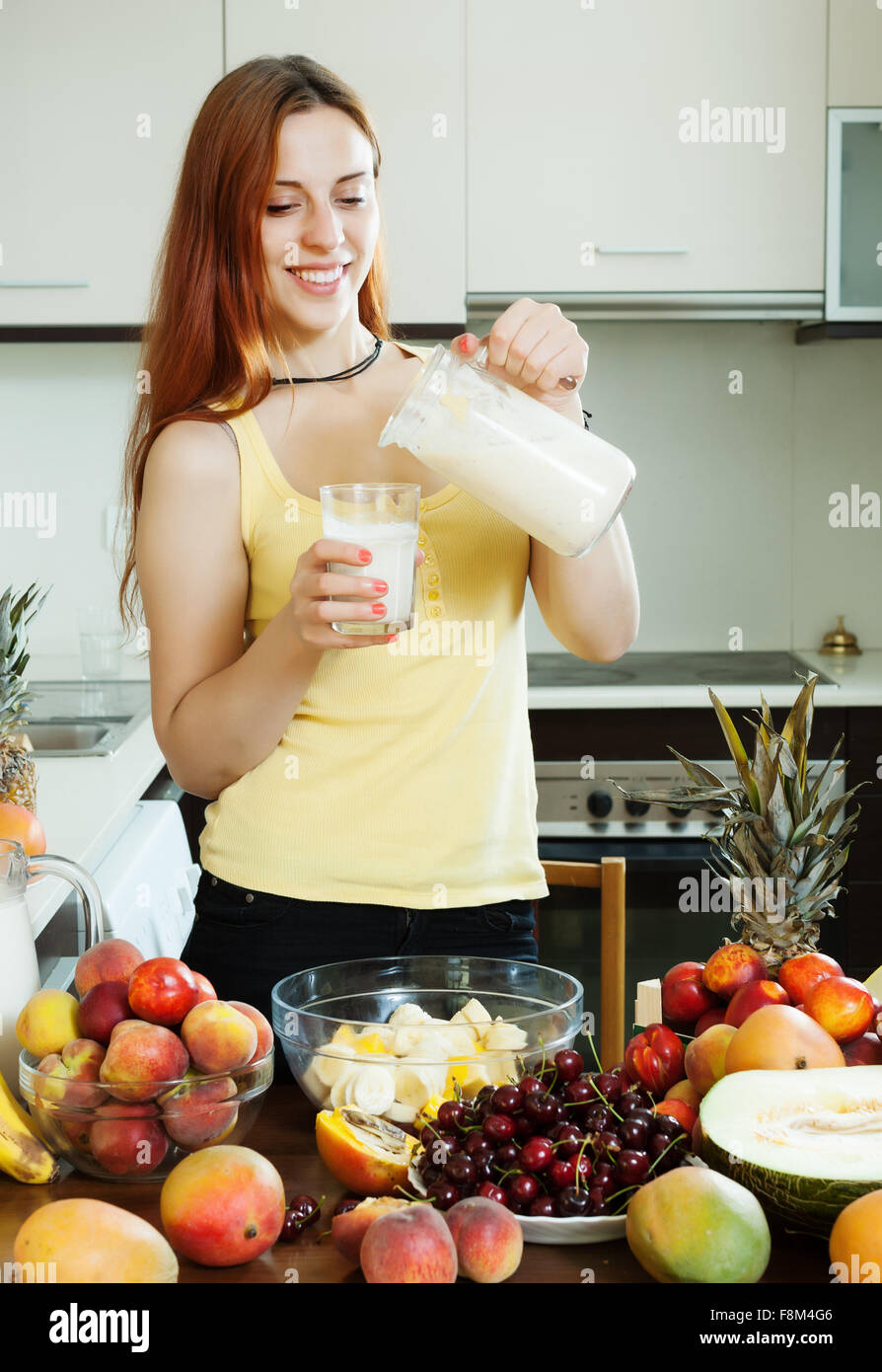 Froh, dass Frau trinkt Milch cocktail mit Früchten und Milch zu Hause Küche Stockfoto