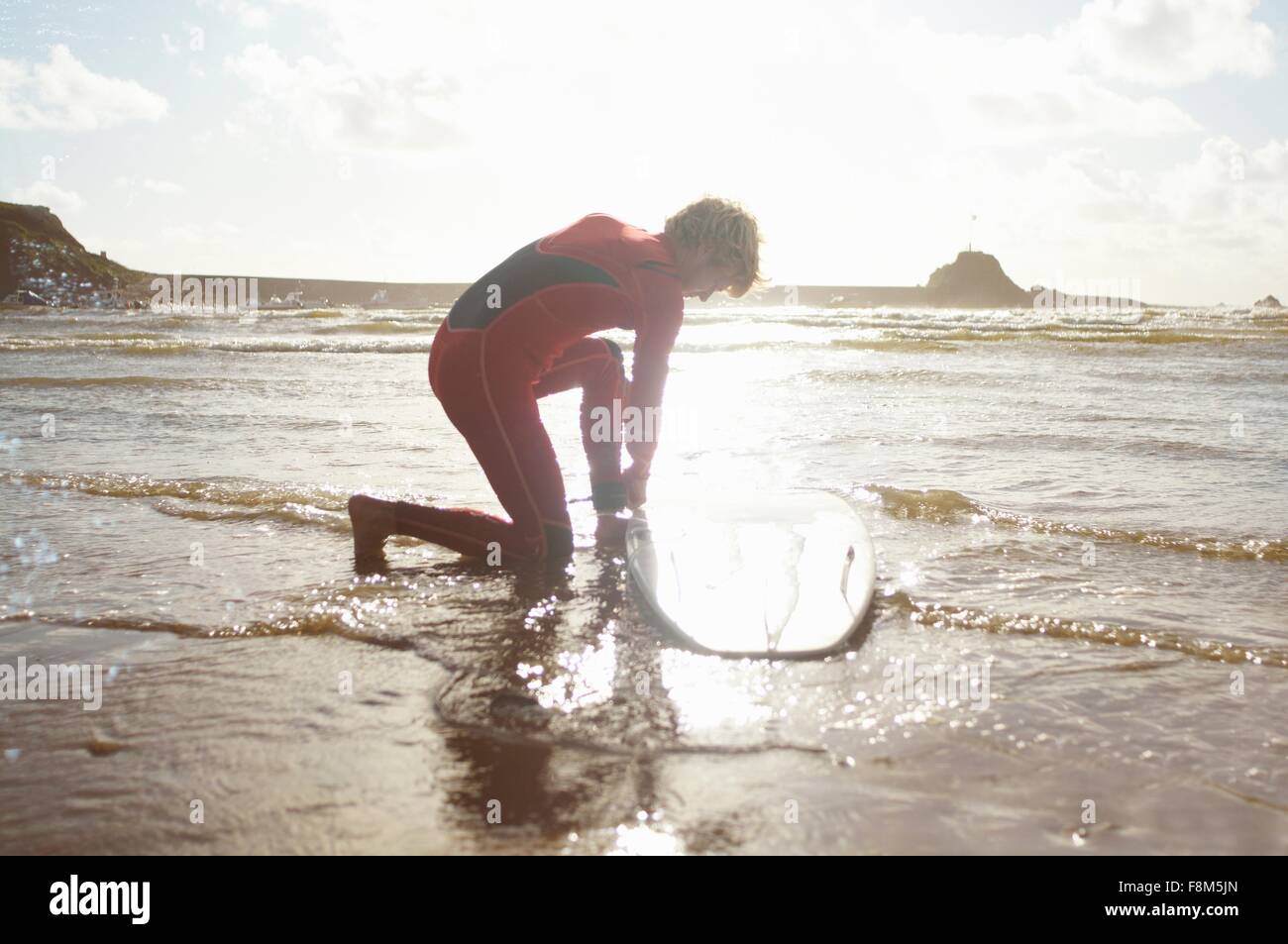 Männliche Surfer Aufbindung Surfbrett vom Knöchel Stockfoto