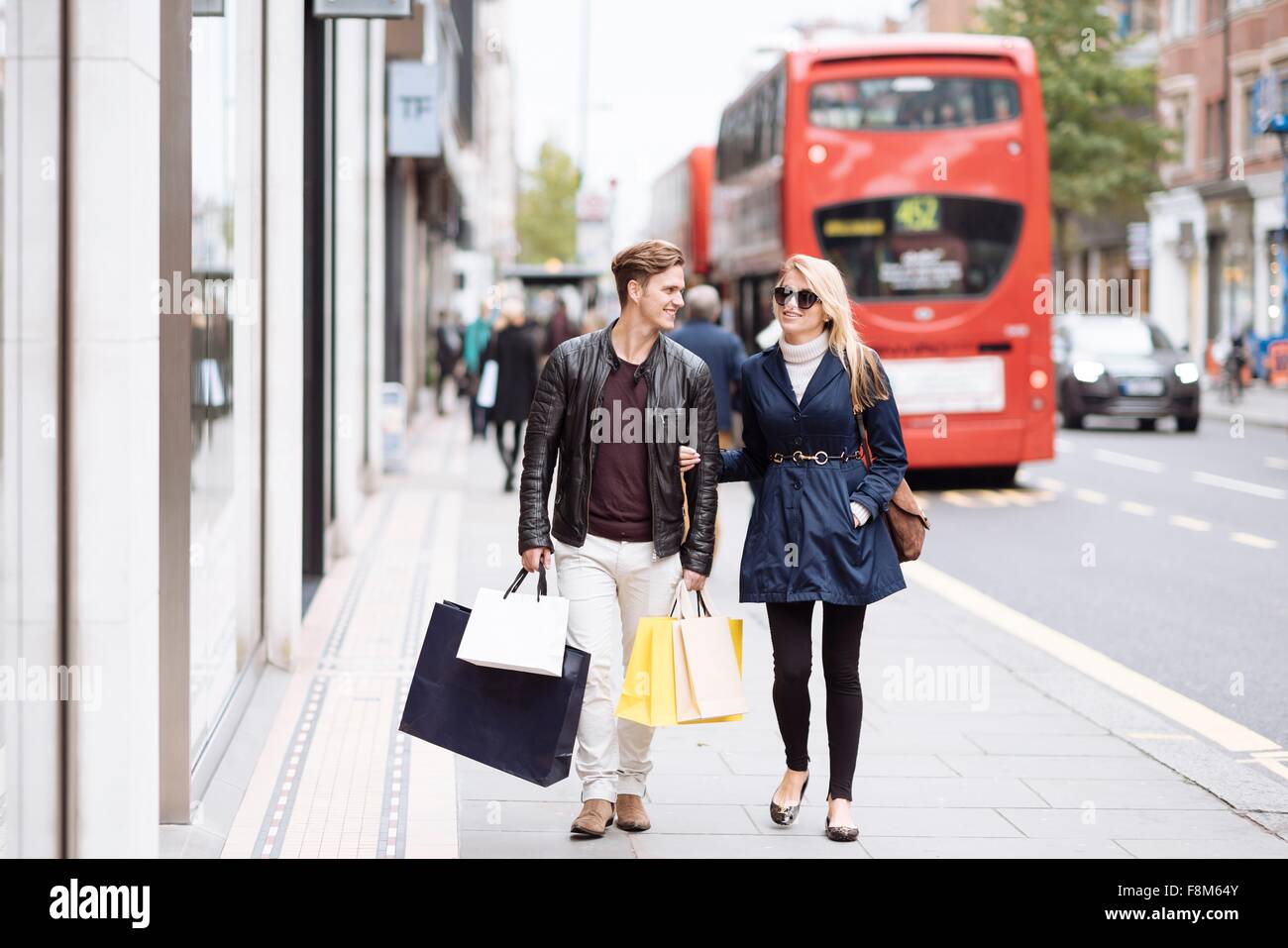 Junges Paar mit Einkaufstaschen flanieren, London, England, UK Stockfoto