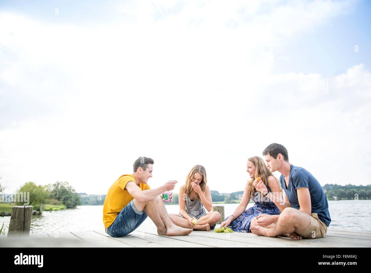 Gruppe junger Erwachsener am Steg sitzen, relaxen Stockfoto