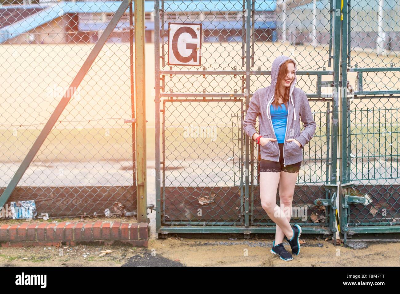 Junge Frau stand neben Sportplatz, London, UK Stockfoto