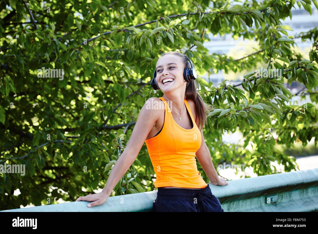 Glückliche junge weibliche Läufer Kopfhörer anhören Stockfoto