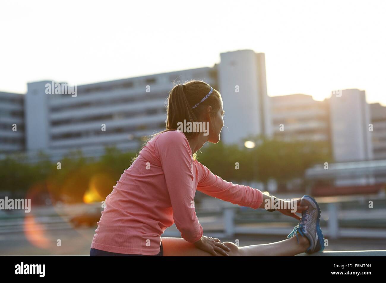 Junge weibliche Läufer berühren Zehen auf Dach Stockfoto