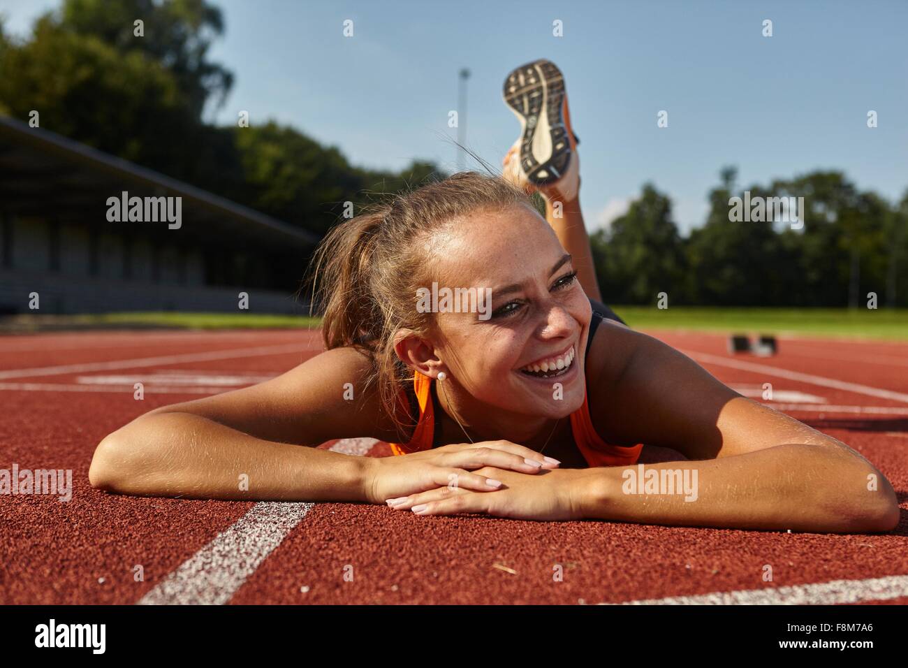 Junge weibliche Läufer liegen auf Vorderseite auf Rennstrecke Stockfoto