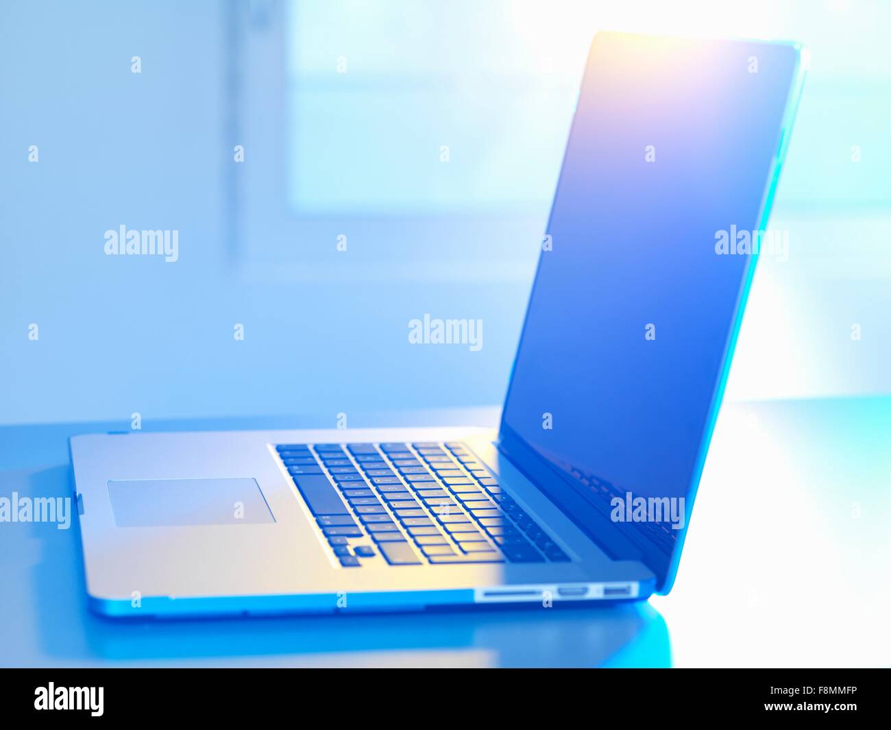 Seitenansicht des offenen Laptop am Schreibtisch, Sonnenlicht, das durch Fenster Stockfoto