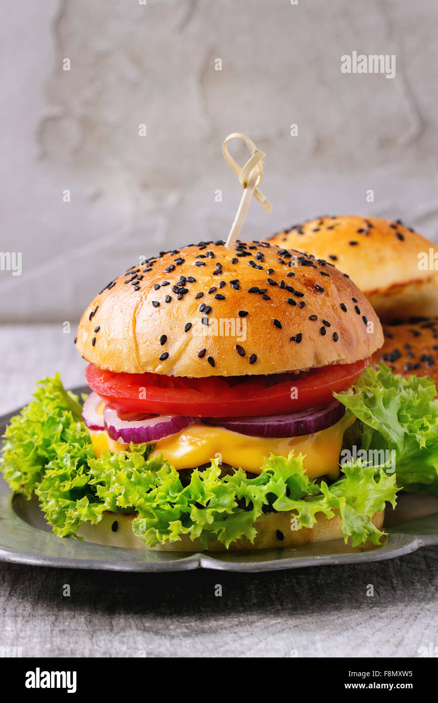 Frische hausgemachte Burger mit schwarzem Sesam in Vintage Metallplatte über graue Holztisch gedient. Rustikalen Stil. Stockfoto
