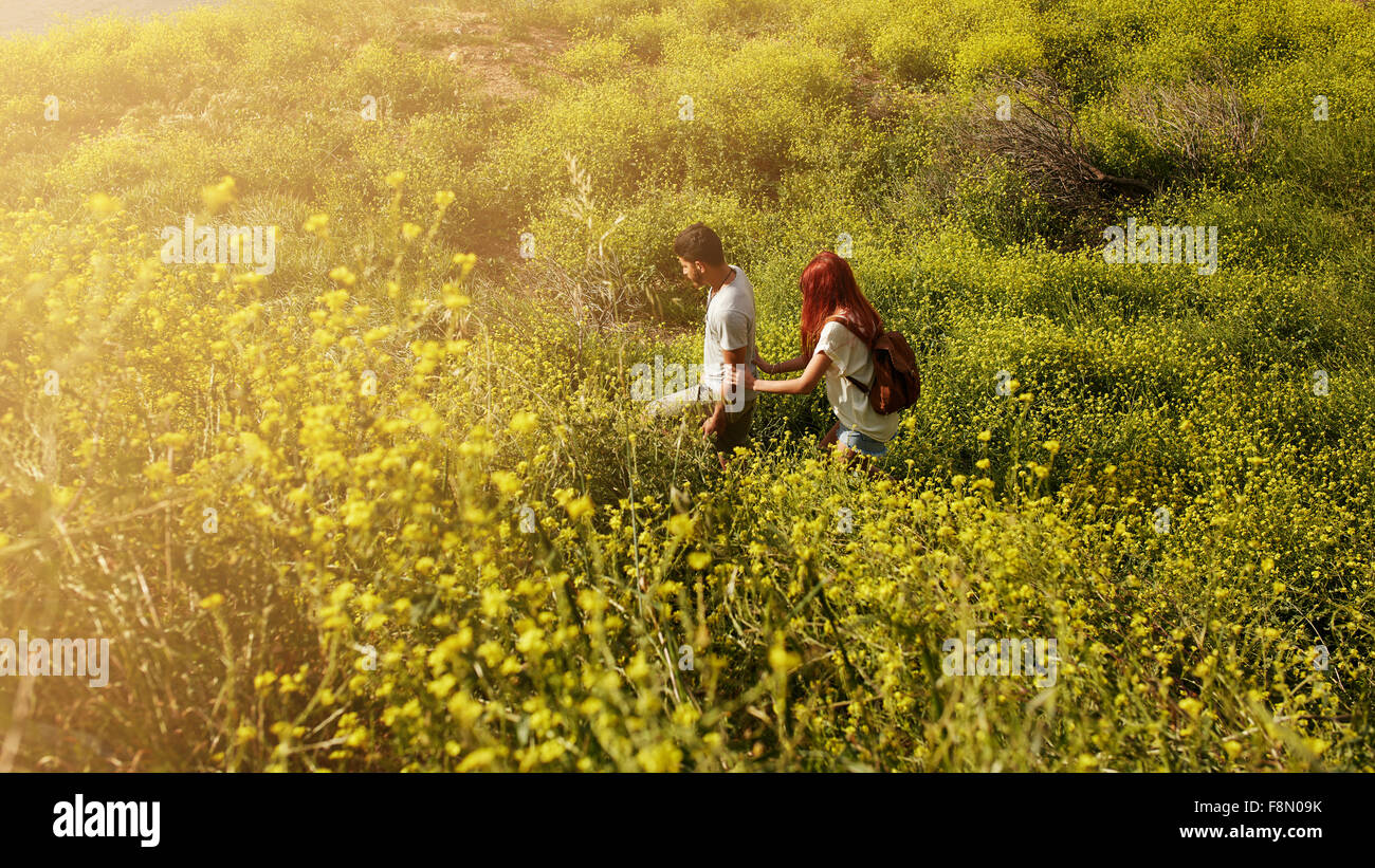 Aufnahme des jungen Paares zu Fuß durch Rasen auf einem Gipfel. Junger Mann und Frau Wandern an einem Sommertag. Stockfoto