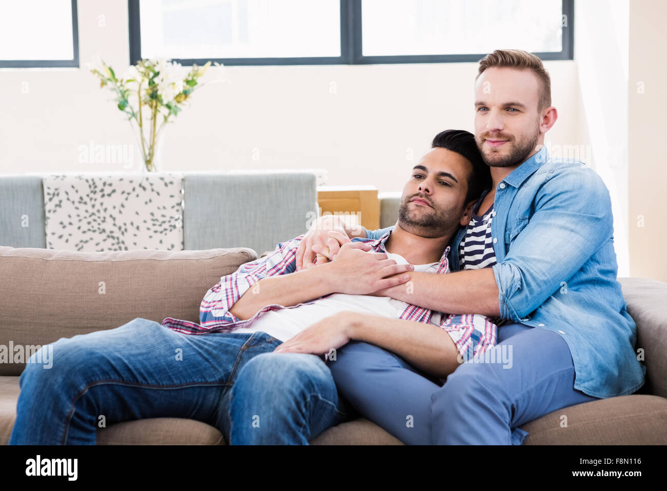 Gay couple hugging on couch -Fotos und -Bildmaterial in hoher Auflösung –  Alamy