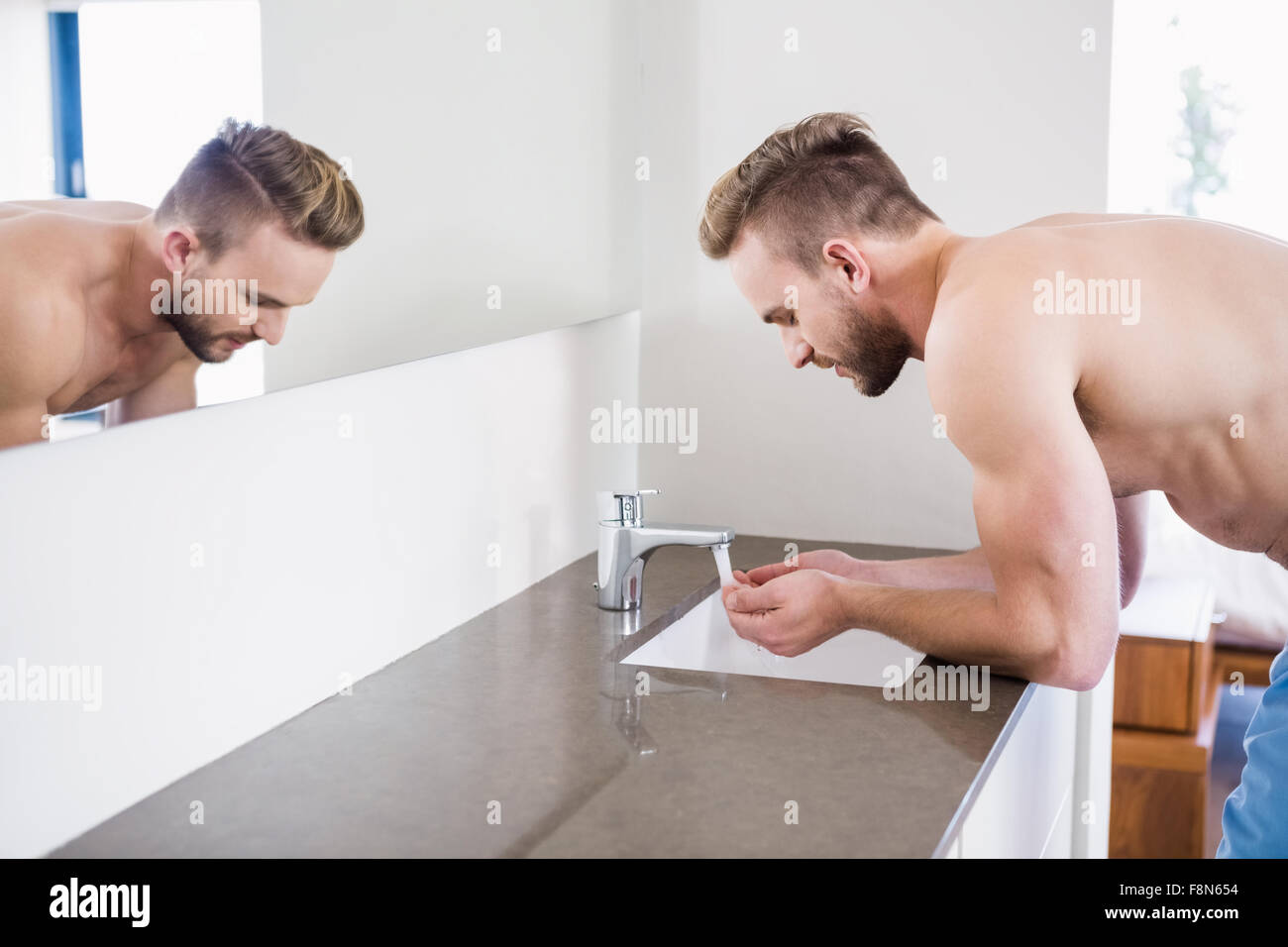 Mann sein Gesicht im Waschbecken waschen Stockfoto