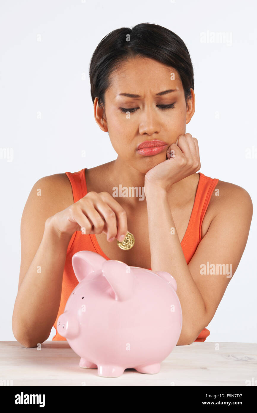Unglückliche, Münze ins Sparschwein Stockfoto