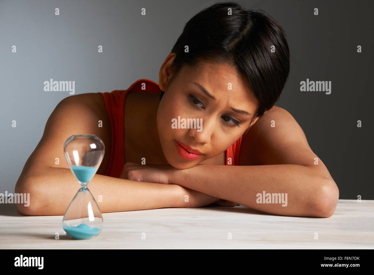Traurige Frau betrachten Sanduhr Stockfoto