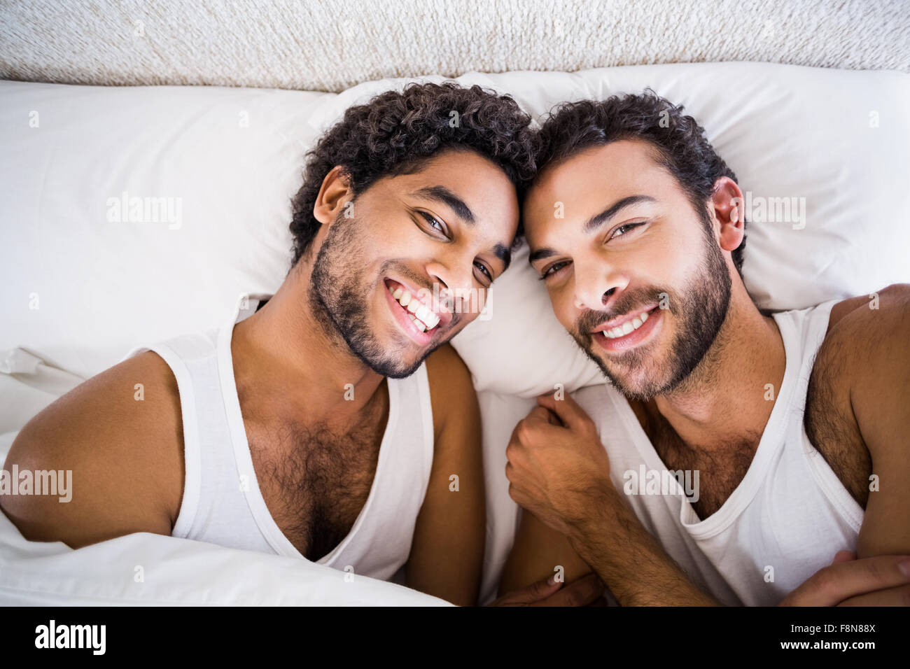 Lächelnde schwules Paar auf Bett Stockfoto
