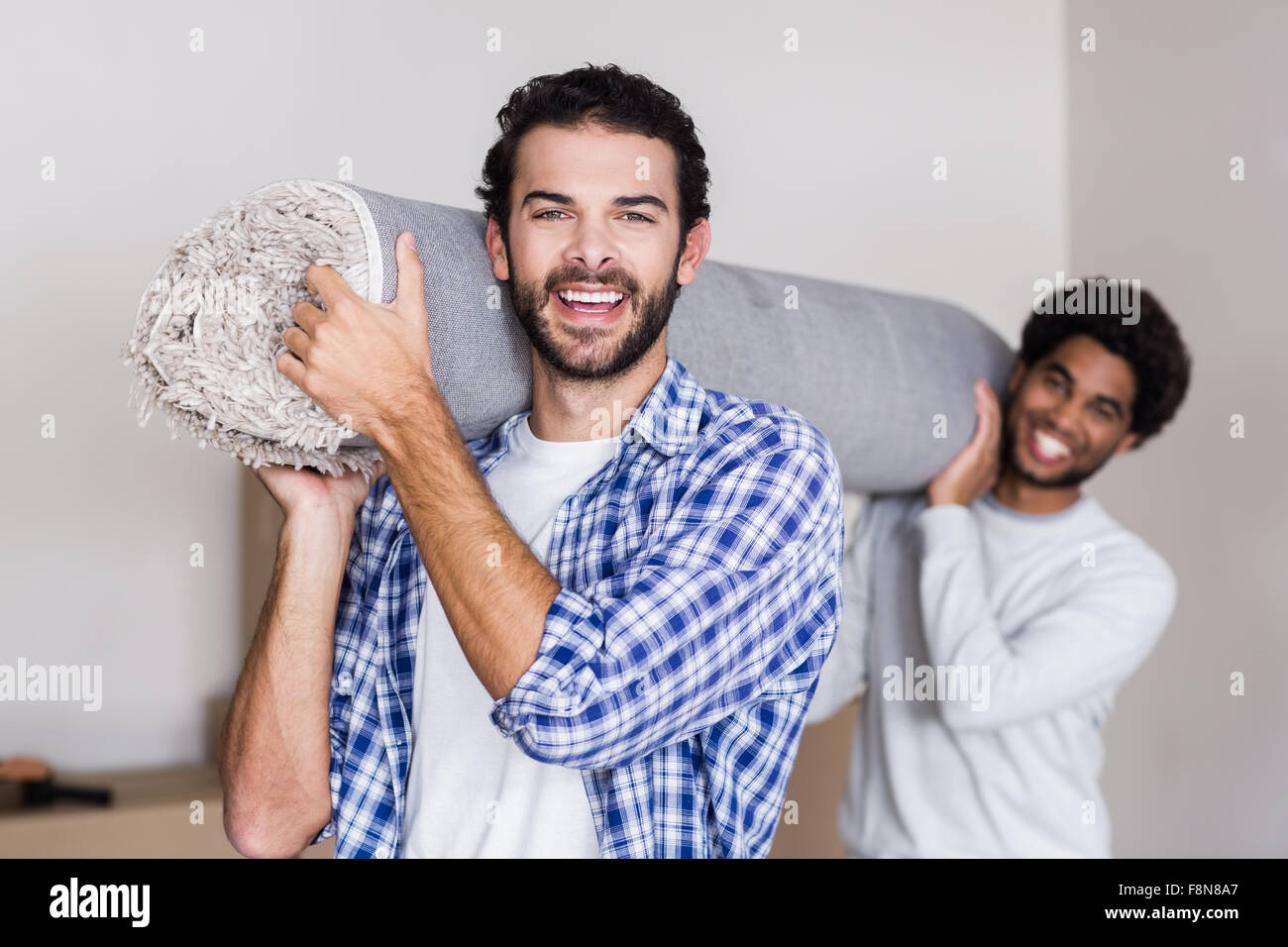 Glückliches schwules Paar mit Teppich Stockfoto