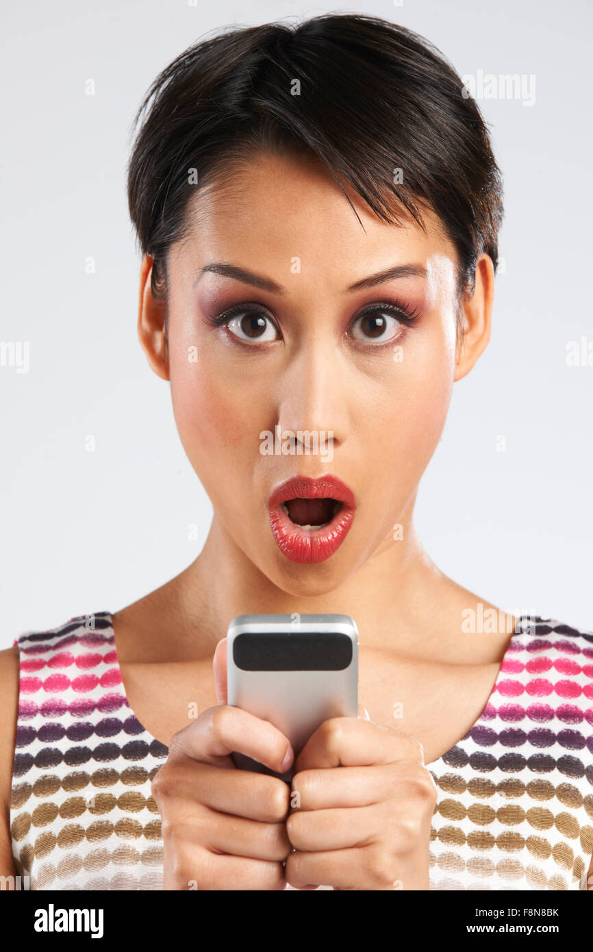 Frau liest SMS mit schockiert Ausdruck Stockfoto