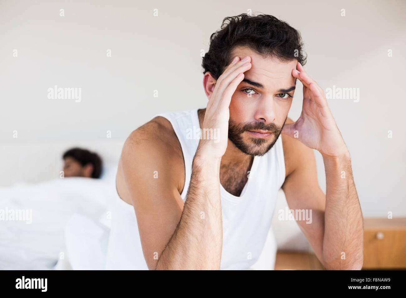 Unruhigen Mann sitzt am Bett im Vordergrund Stockfoto