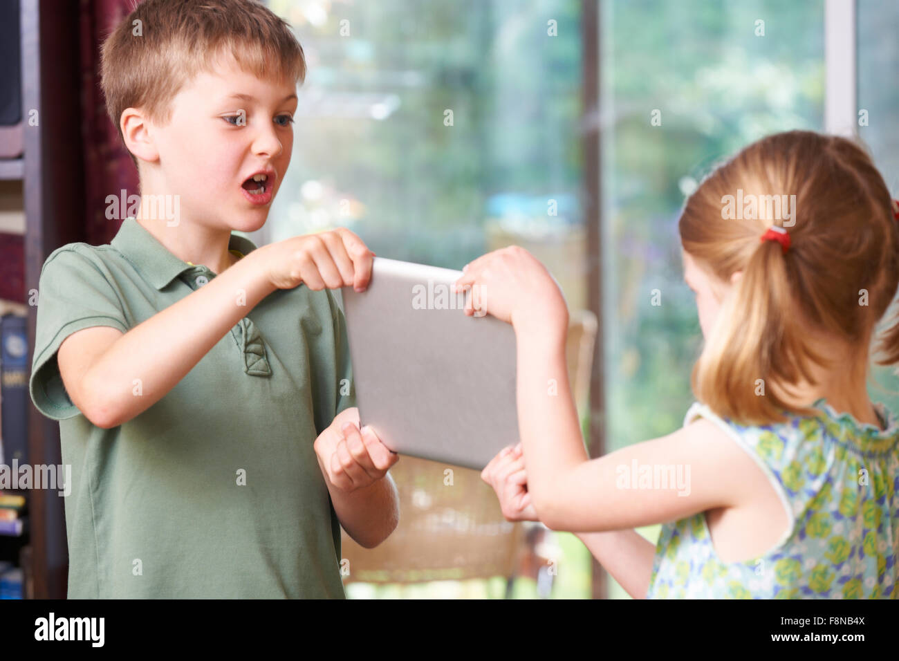 Jungen und Mädchen kämpfen über Digital-Tablette Stockfoto