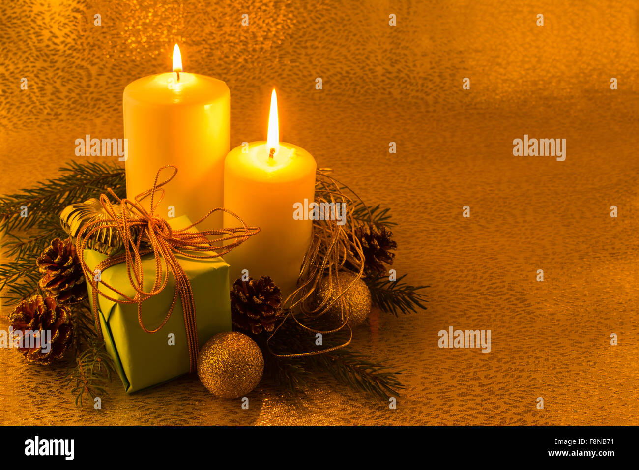 Kopieren Sie brennen weiße Weihnachtskerzen, grüne Geschenkbox, Goldene Kugeln, Tannenzweigen und Zapfen auf einem dunklen Hintergrund gold, Raum Stockfoto