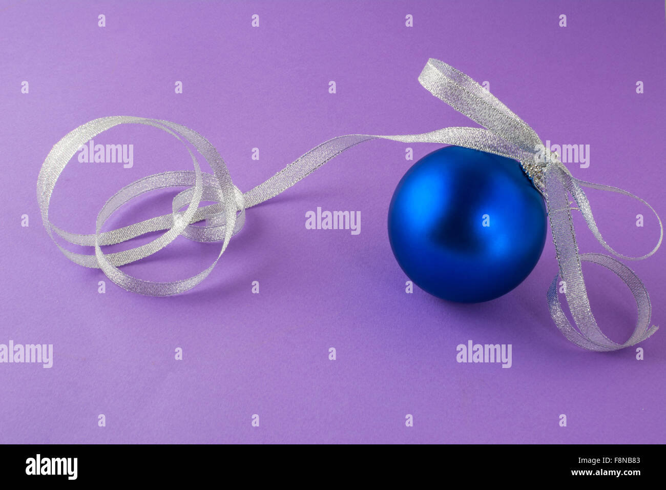 Ornament tiefblauen Weihnachtskugel mit Silber Schleife auf lila Hintergrund Stockfoto