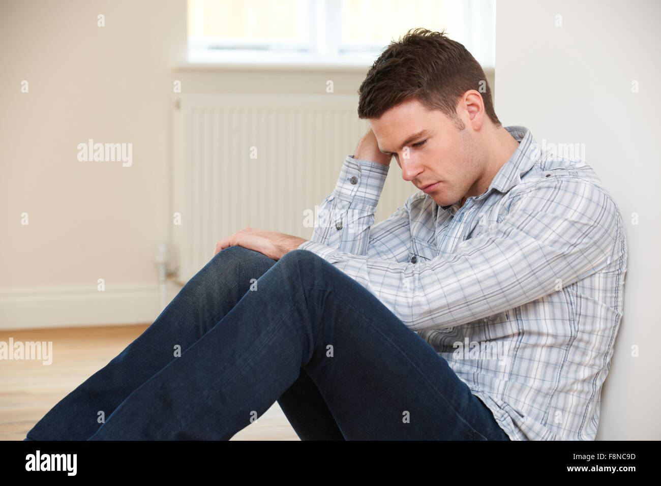 Deprimiert Mann sitzt im leeren Raum Repossessed Haus Stockfoto