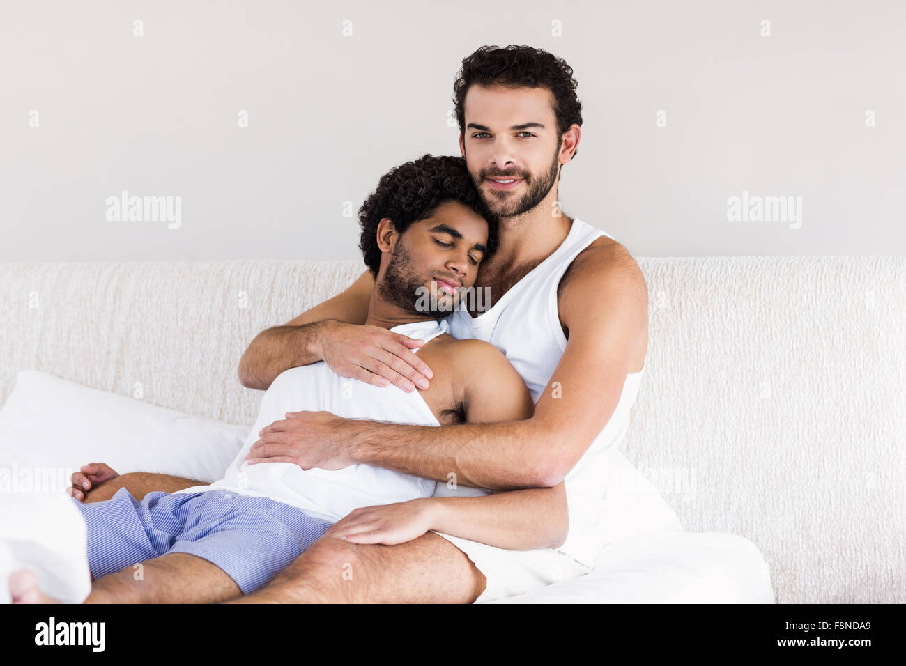 Lächelnder Mann umarmt seinen verschlafenen partner Stockfoto
