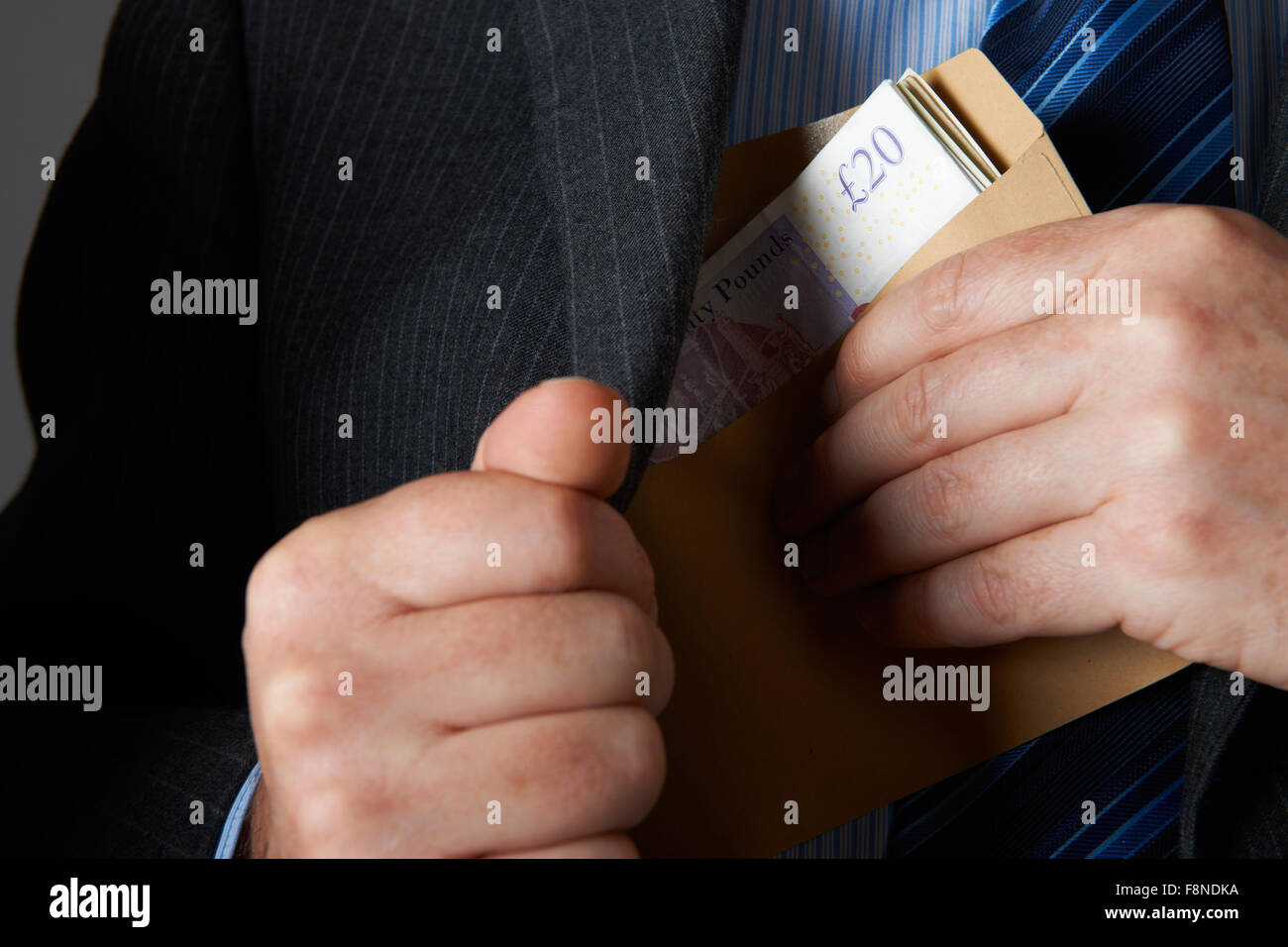 Unternehmer setzen Umschlag von Sterling Noten In der Jackentasche Stockfoto