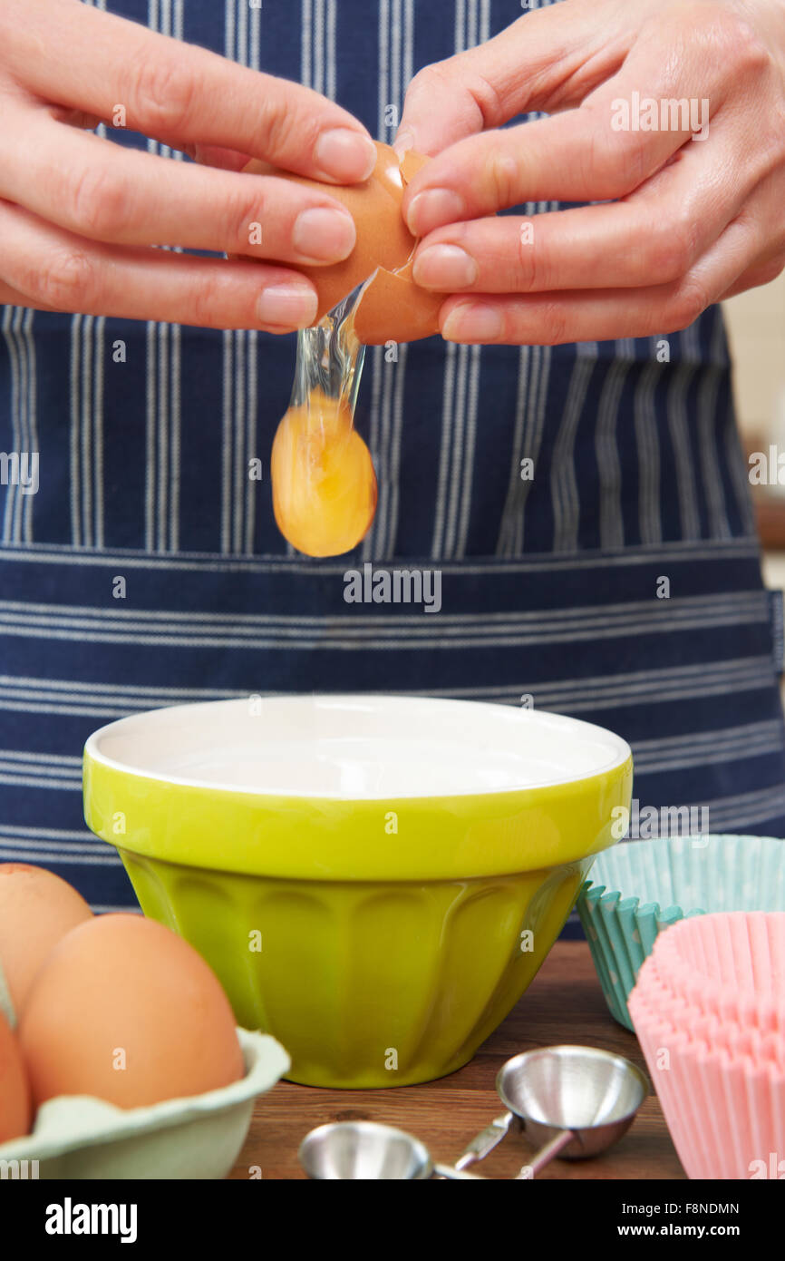 Frau Ei in Schale zu knacken, während Kochen Stockfoto