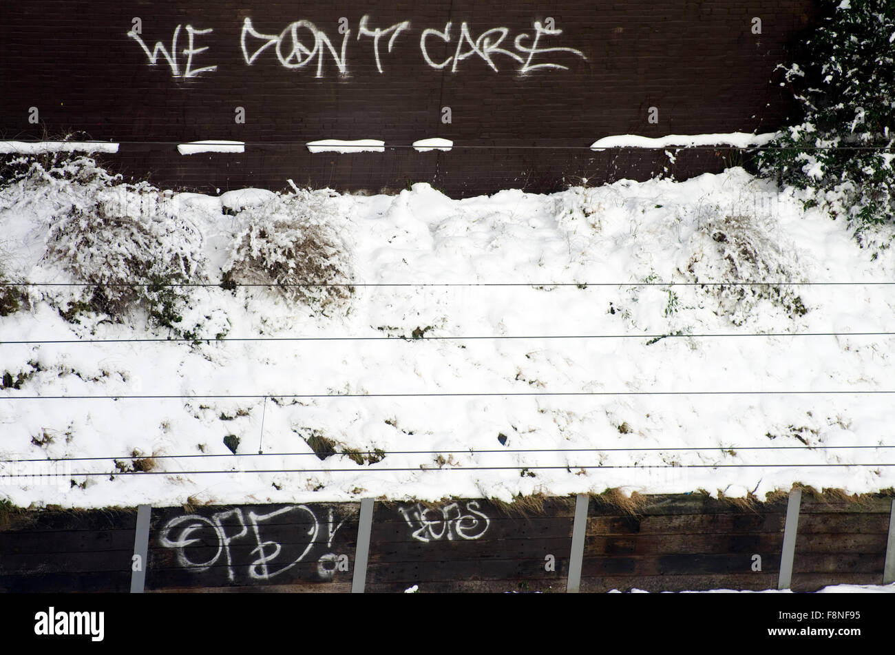 Wir kümmern uns nicht, Graffiti auf einer braunen Wand neben einigen Gleisanlagen, mit Schnee bedeckt Stockfoto