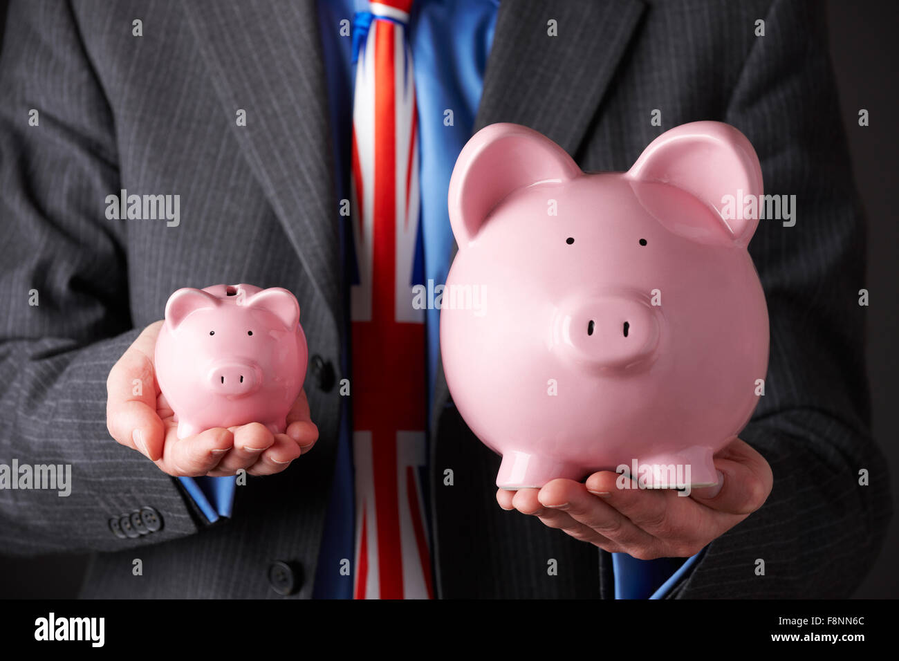 Britischer Unternehmer halten große und kleine Sparschwein Stockfoto