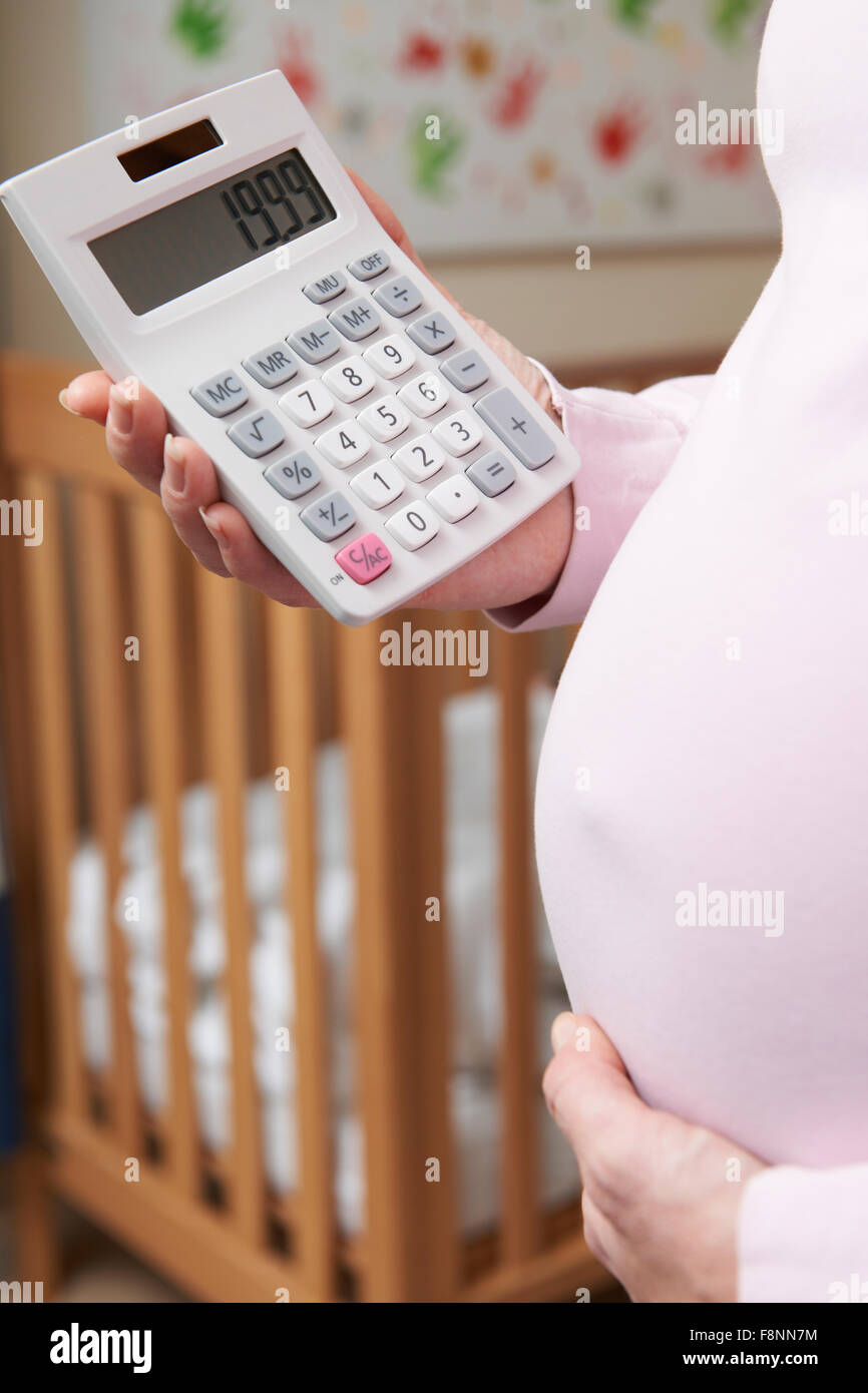 Schwangere Frau im Kindergarten mit Taschenrechner Stockfoto
