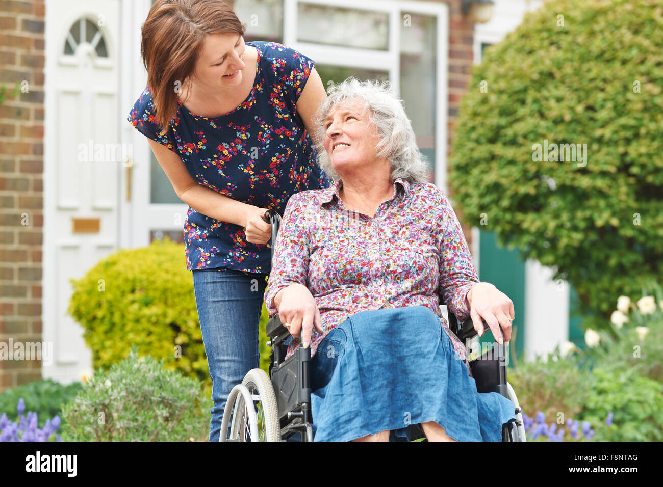 Erwachsene Tochter, die Mutter im Rollstuhl schieben Stockfoto