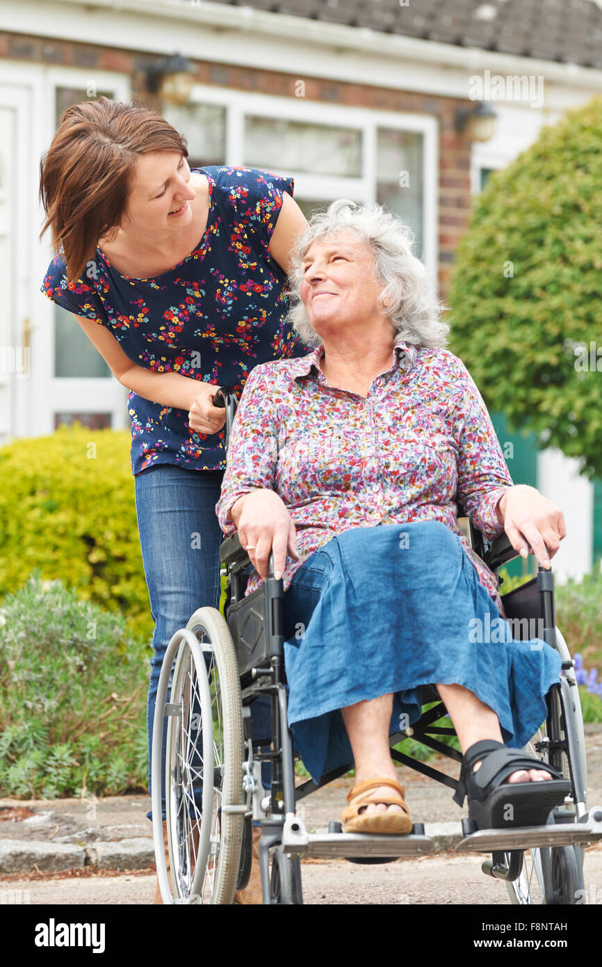 Erwachsene Tochter, die Mutter im Rollstuhl schieben Stockfoto