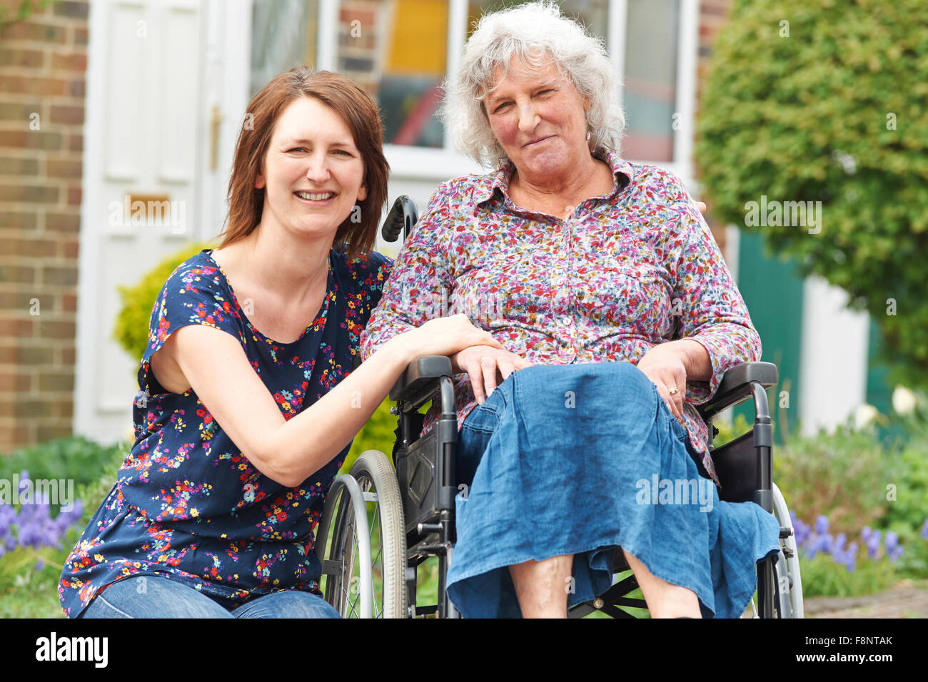 Erwachsene Tochter, die Mutter im Rollstuhl schieben Stockfoto