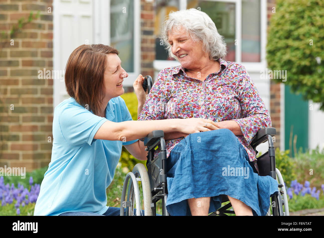 Pflegeperson mit Senior Frau im Rollstuhl Stockfoto
