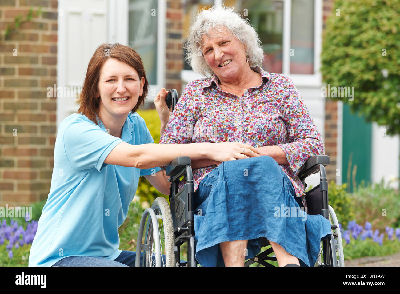 Pflegeperson mit Senior Frau im Rollstuhl Stockfoto
