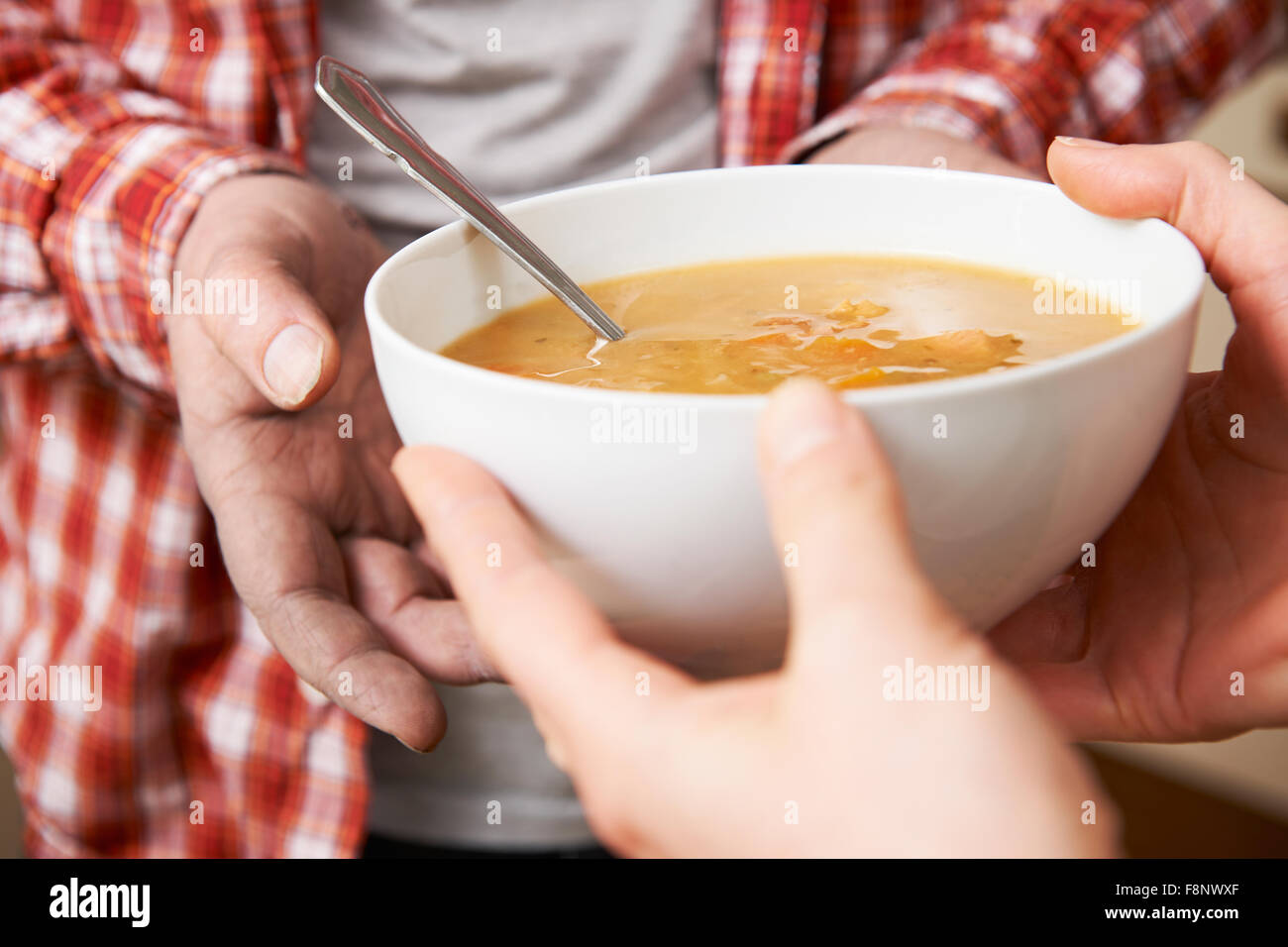 Obdachlosen Mann übergeben Teller Suppe von Freiwilligen Stockfoto