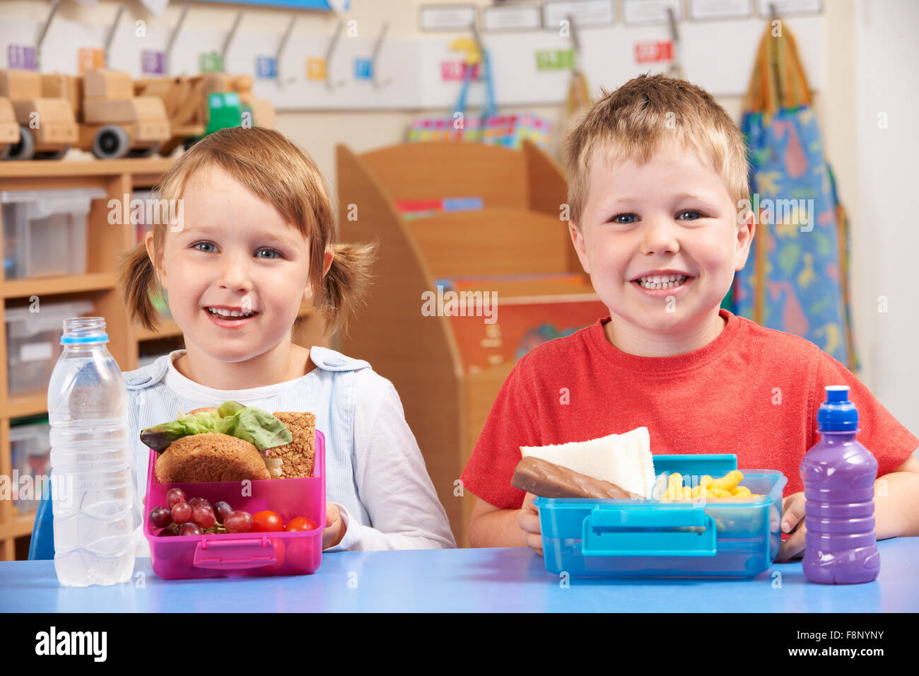 Grundschüler mit gesunden und ungesunden Mittagessen Boxen Stockfoto