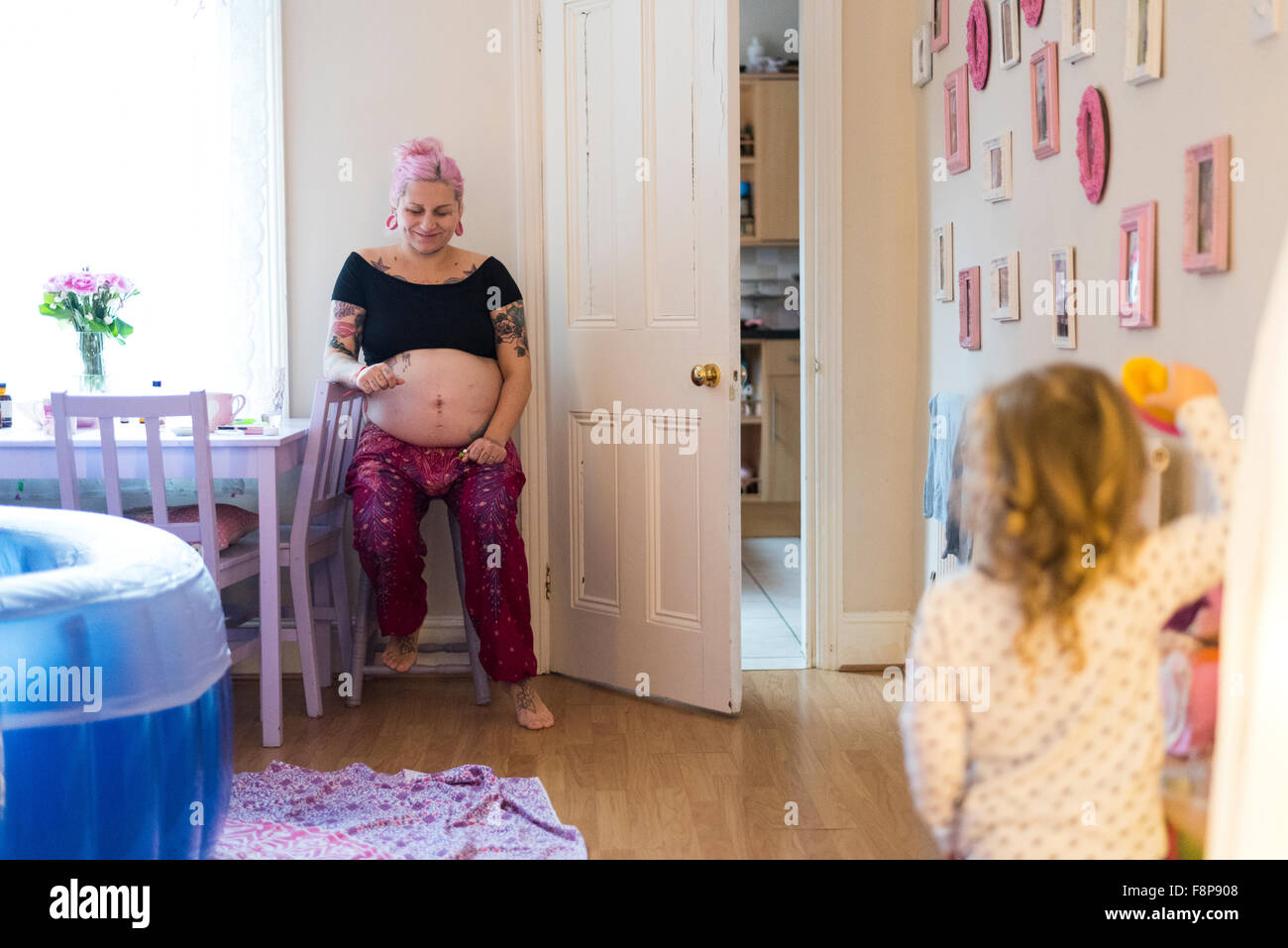 Schwangere Frau in der Arbeit mit ihrem Sohn im Zimmer während einer ohne fremde Hilfe Hausgeburt (Freebirth) Stockfoto