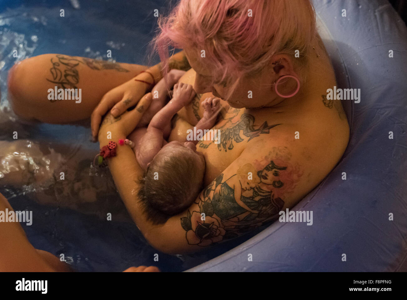 Mutter mit ihrem Neugeborenen Baby in eine Birthpool nach der Geburt in eine selbständige Hausgeburt (Freebirth). Stockfoto