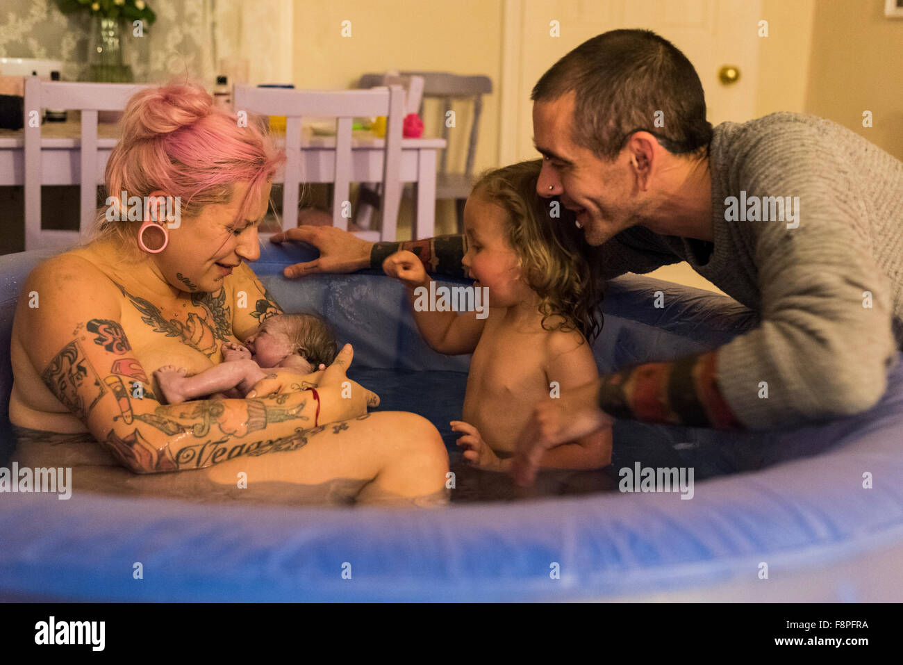 Familie betrachten ihre Neugeborenen in einem Birthpool nach einem ohne fremde Hilfe Hausgeburt (Freebirth). Stockfoto