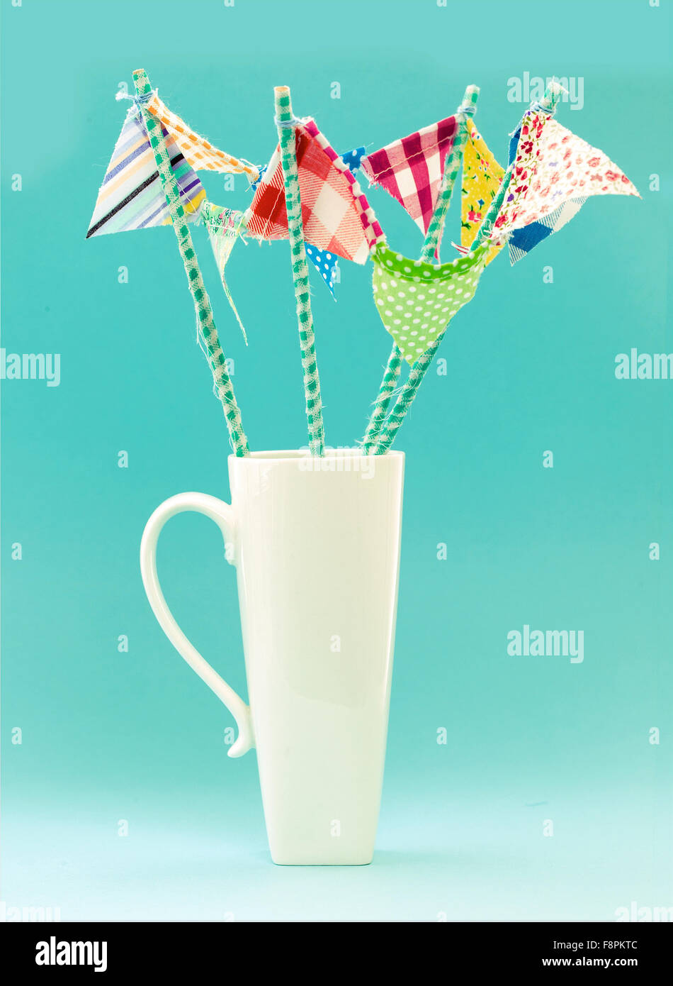 Weiße Tasse mit handgemachten bunten Fahnen auf Türkis Retro-Hintergrund Stockfoto
