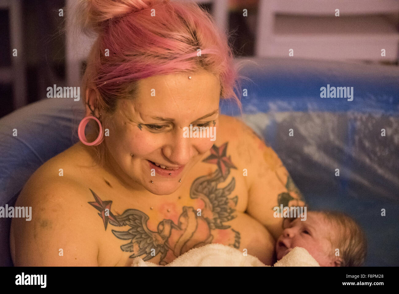 Mutter lächelt nach der Geburt ihr Baby in eine Birthpool in eine selbständige Hausgeburt (Freebirth). Stockfoto