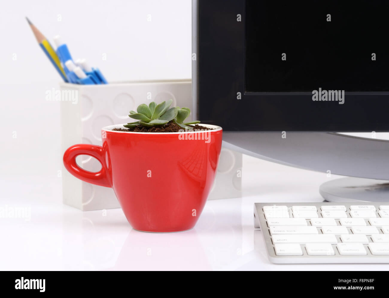 Büro mit kleinen Kaktus in rote Keramik Tasse auf Schreibtisch schön zu machen. Stockfoto