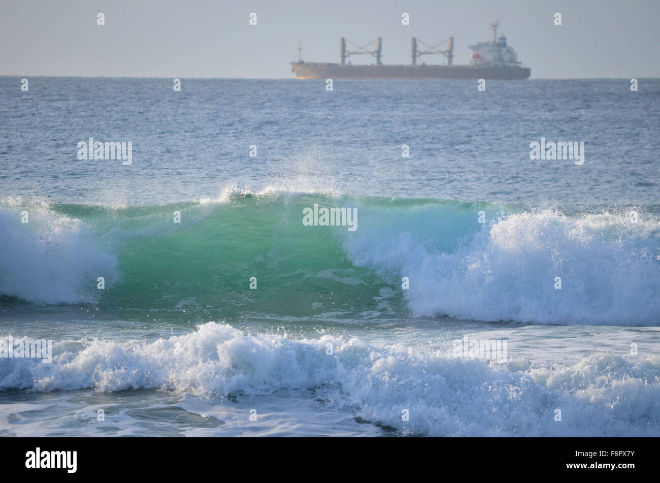Welle bricht im schönen grünen und hellen blauen Farben mit Schiff im Hintergrund Stockfoto