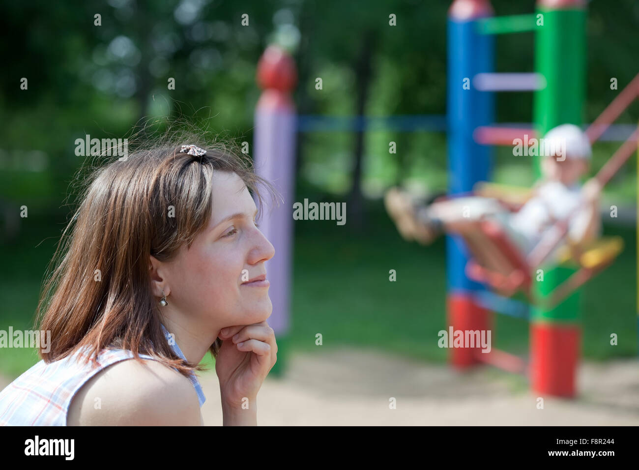 Porträt der Frau gegen Kind auf Schaukel auf dem Spielplatz Stockfoto