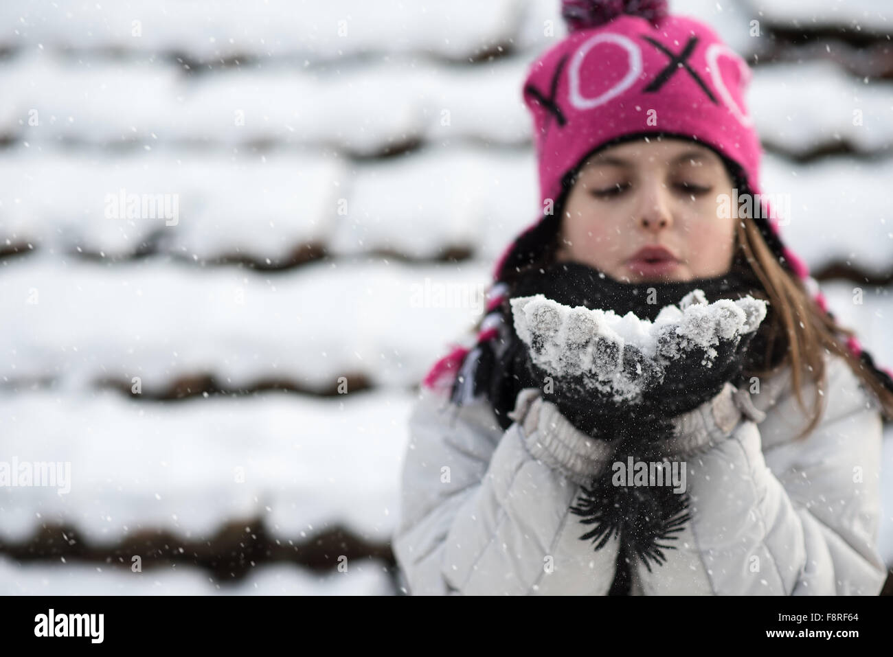 Mädchen bläst Handvoll Schnee Stockfoto