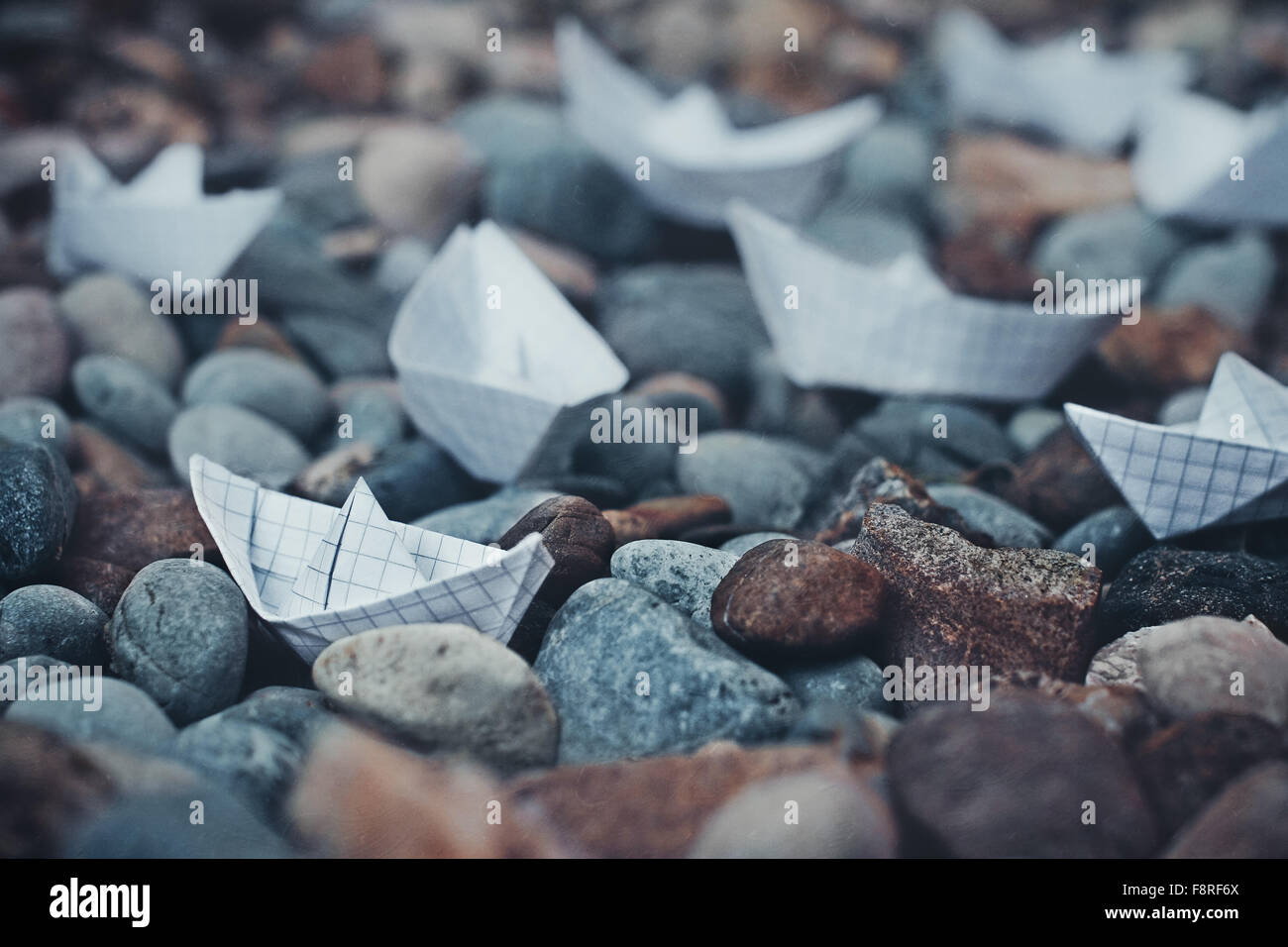 Origami Schiffe und Kieselsteine am Strand Stockfoto
